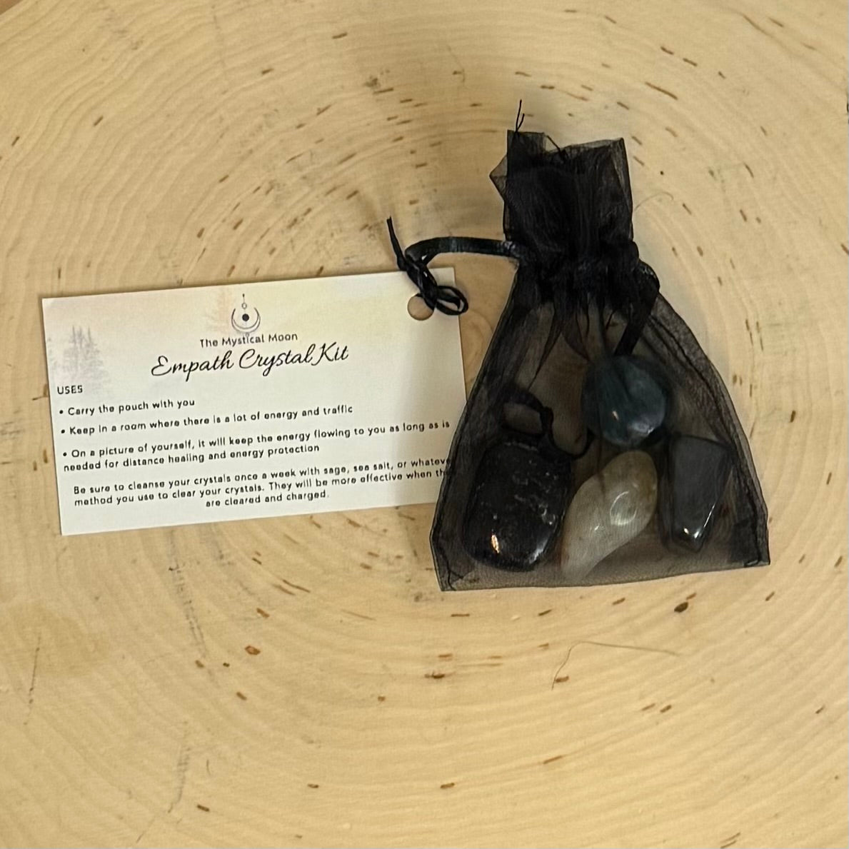 Crystal kit with stones and information card on a wooden surface