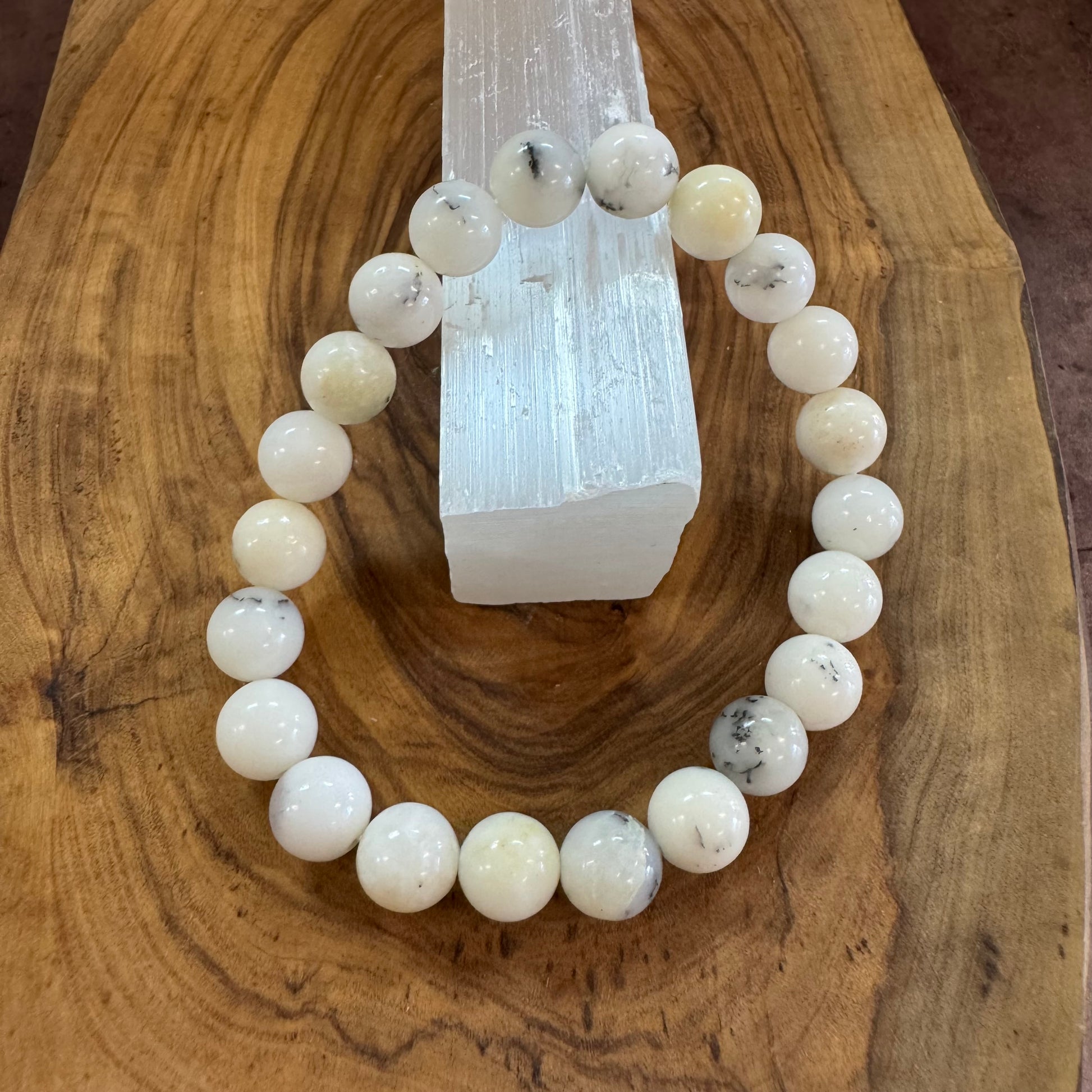 White beaded bracelet on a wooden surface with a crystal in the background