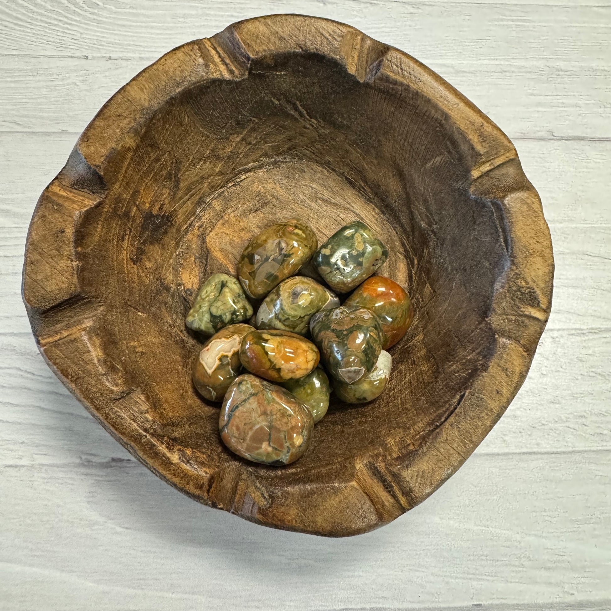 Wooden bowl with stones on a light wooden surface