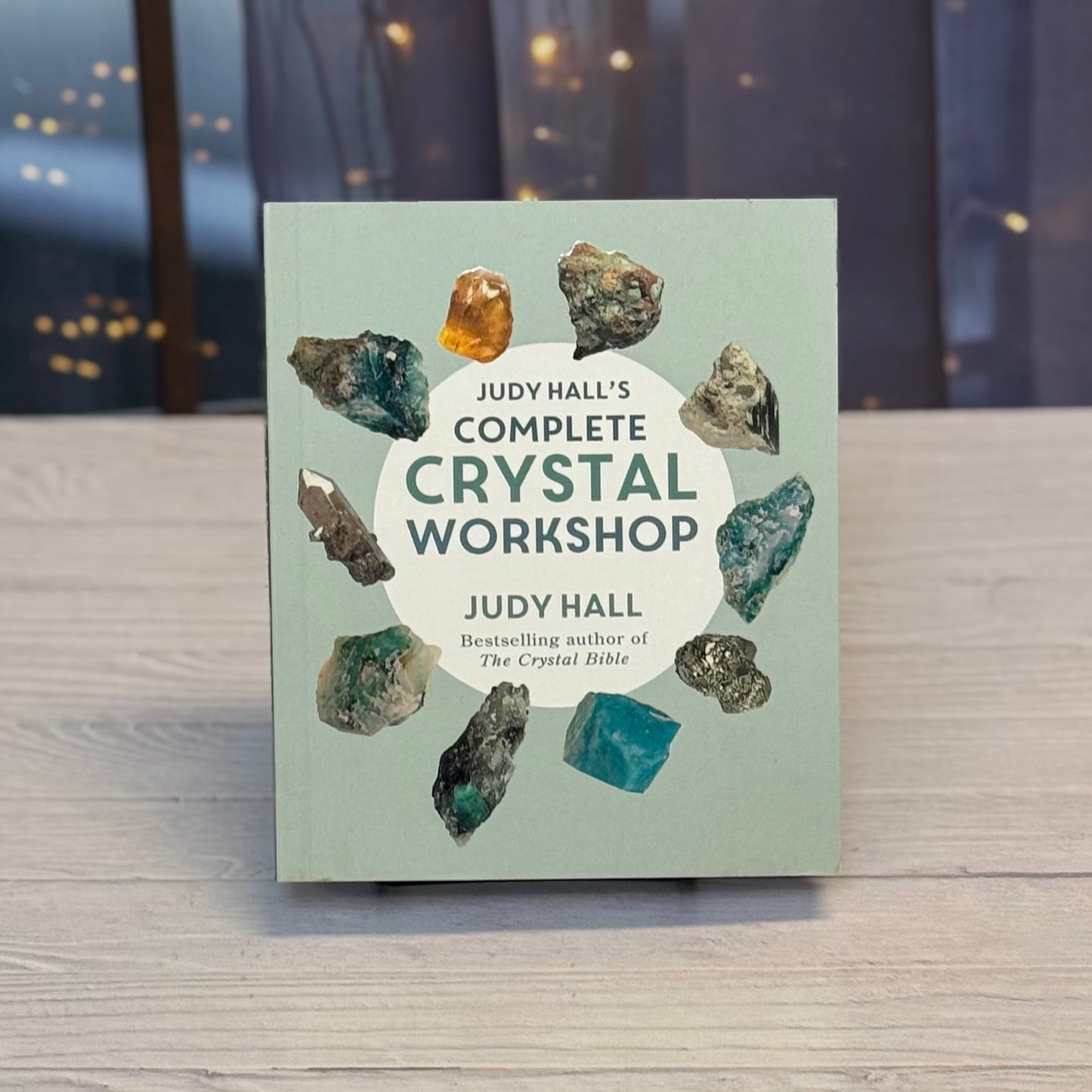 Book titled 'Judy Hall's Complete Crystal Workshop' with crystal images on a wooden surface.