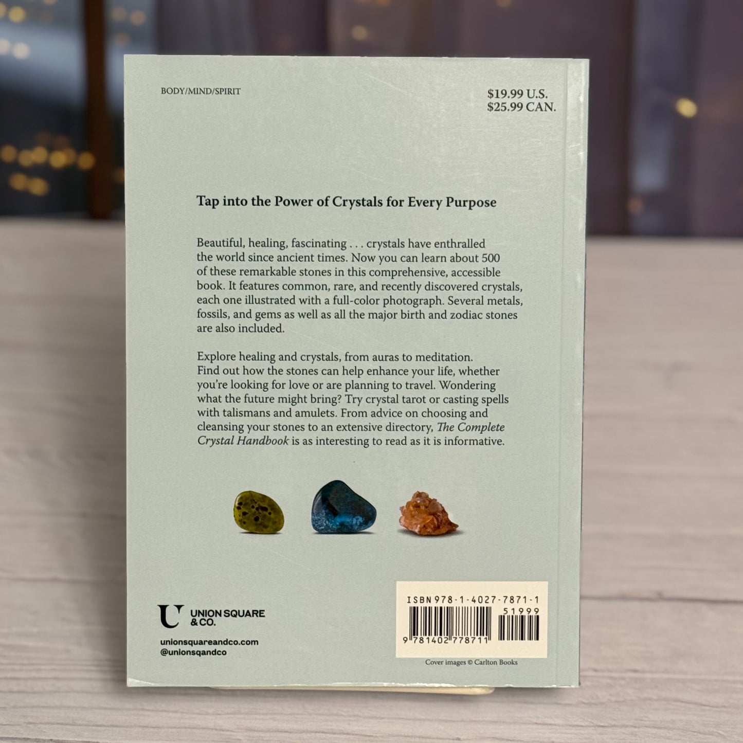 Back cover of a book about crystals with text and illustrations on a wooden surface.