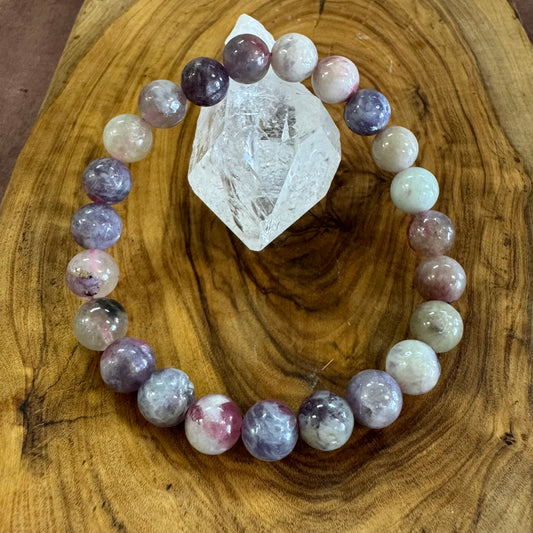 Multicolored beaded bracelet on a wooden surface with a crystal.