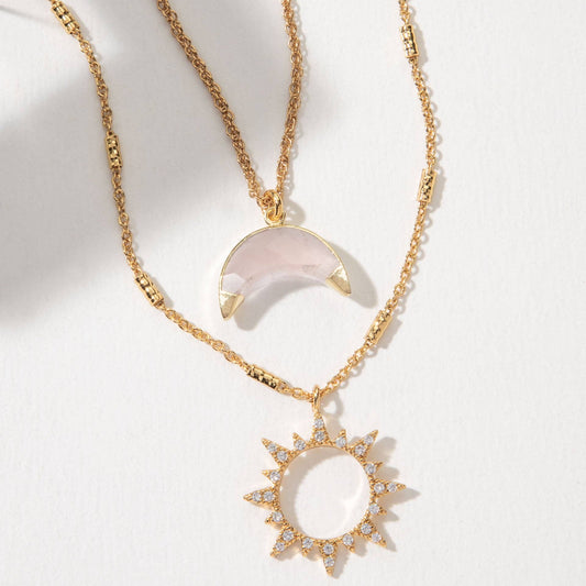 Gold necklace with a sun-shaped pendant on a white background