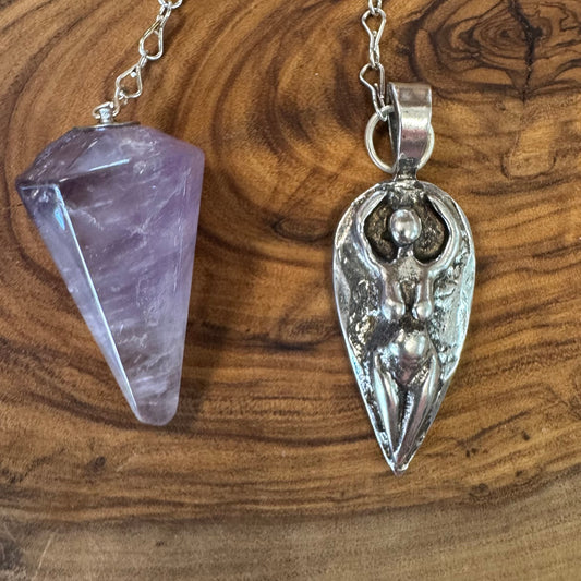Amethyst crystal and silver pendant on a wooden surface