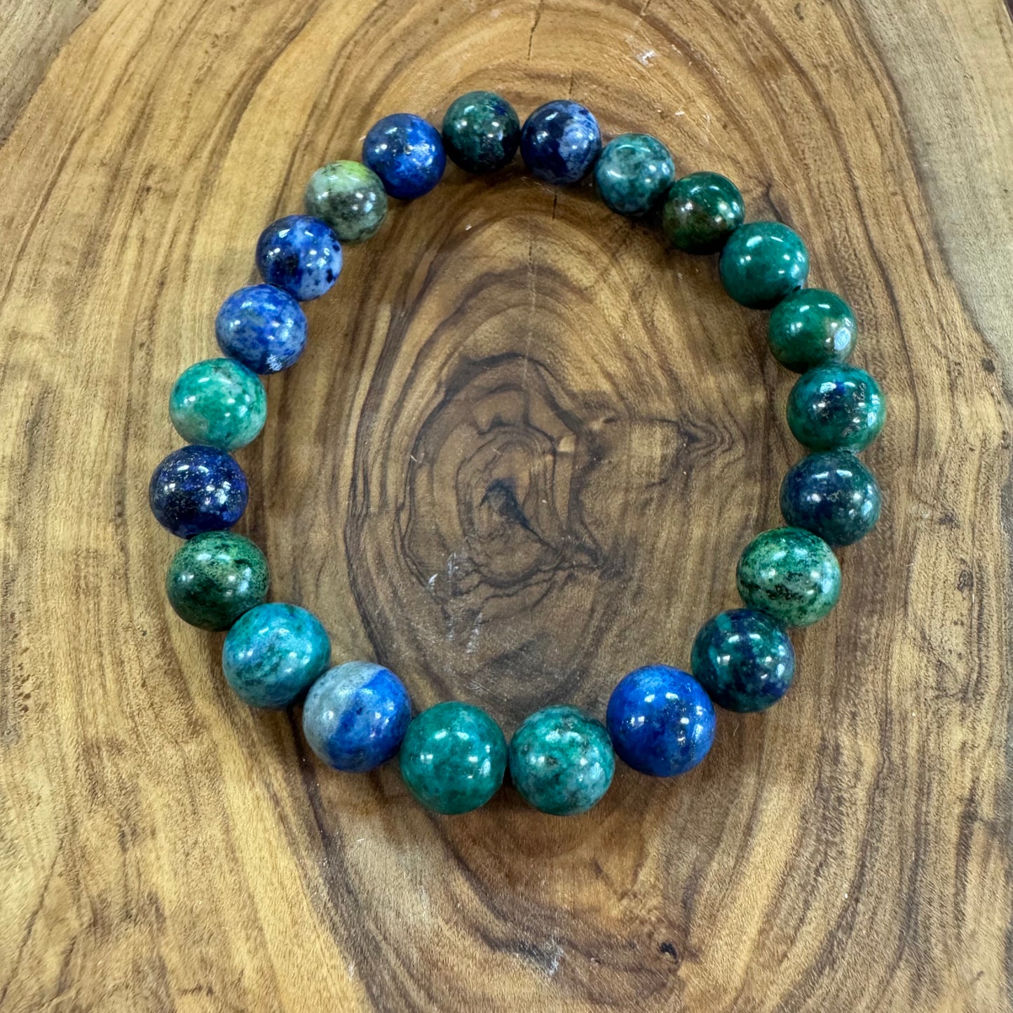 Beaded bracelet with blue and green beads on a wooden surface