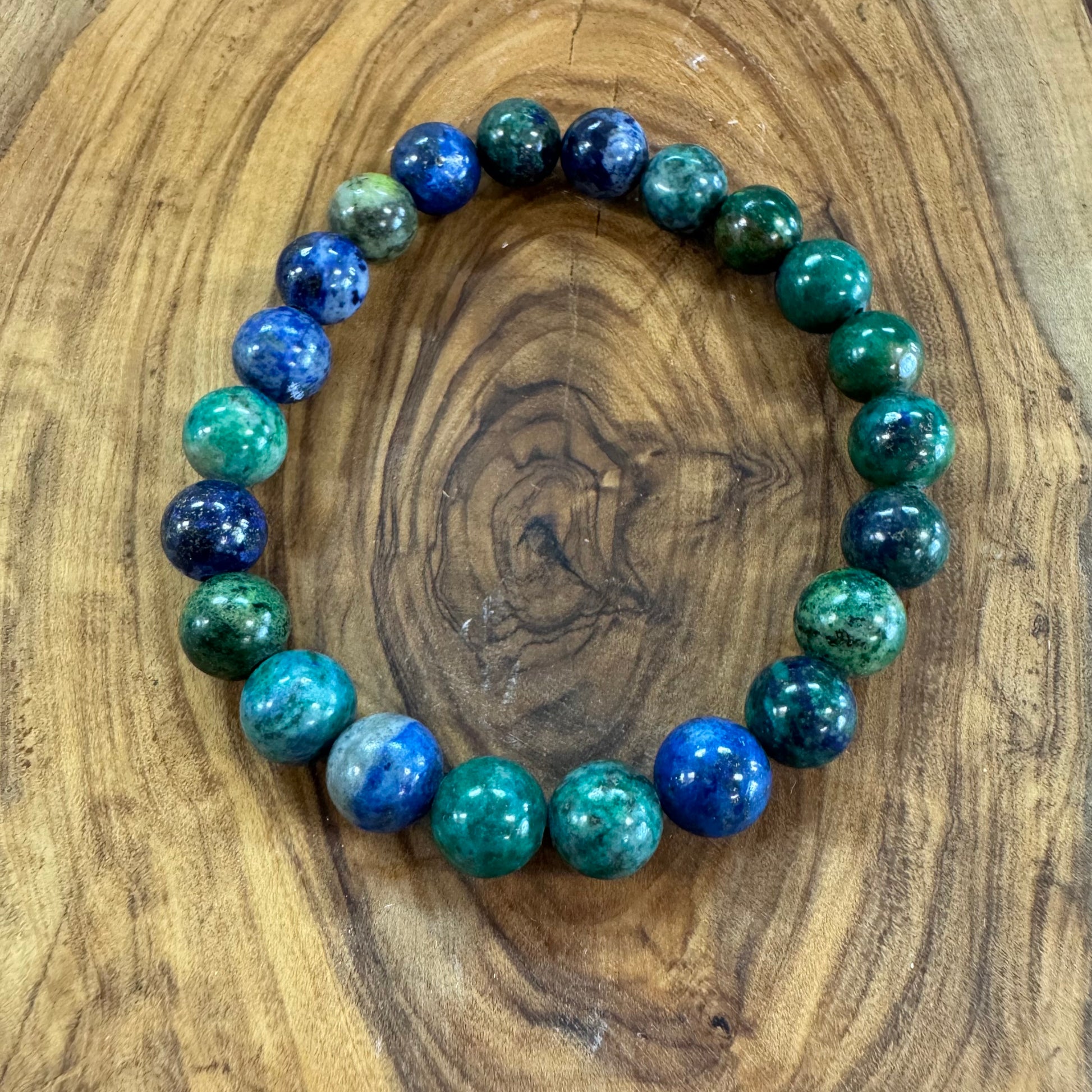 Beaded bracelet with blue and green beads on a wooden surface