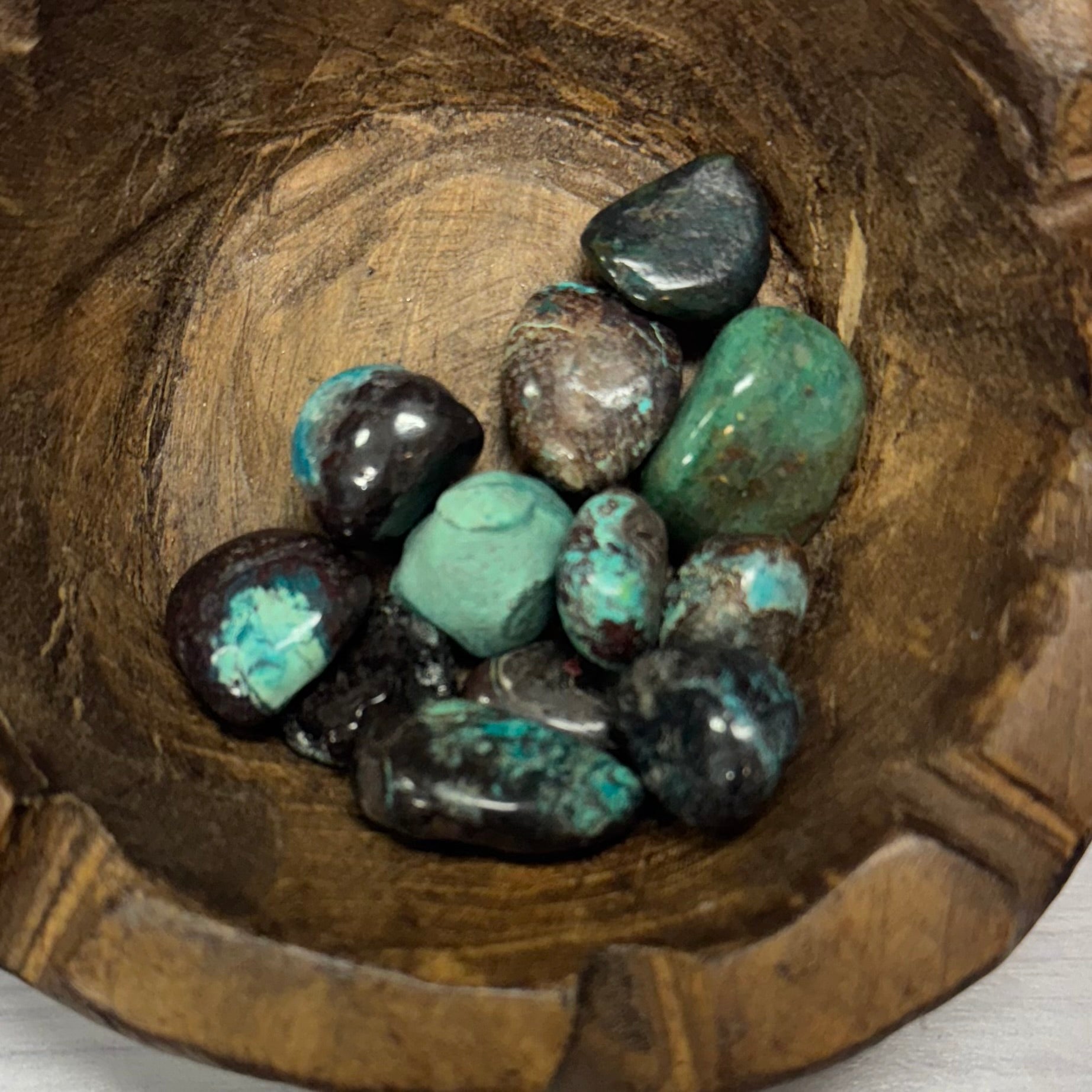Turquoise and black stones in a wooden bowl