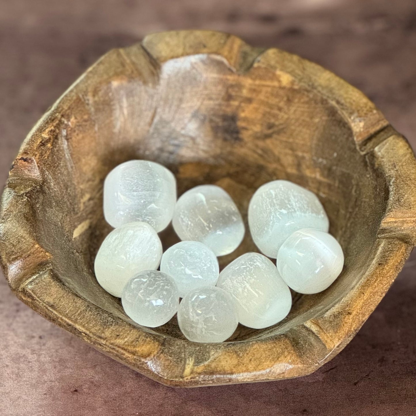 Wooden bowl with selenite stones on a brown surface