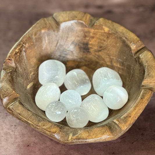 Wooden bowl with selenite stones on a brown surface