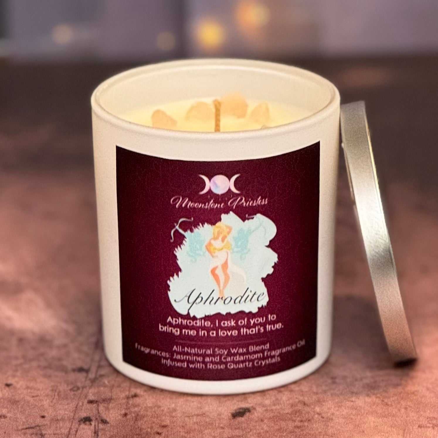 Candle in a white container with a label featuring an illustration of a fairy and text on a wooden surface.