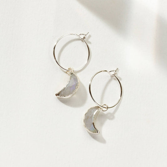 Pair of hoop earrings with moon-shaped stones on a light background