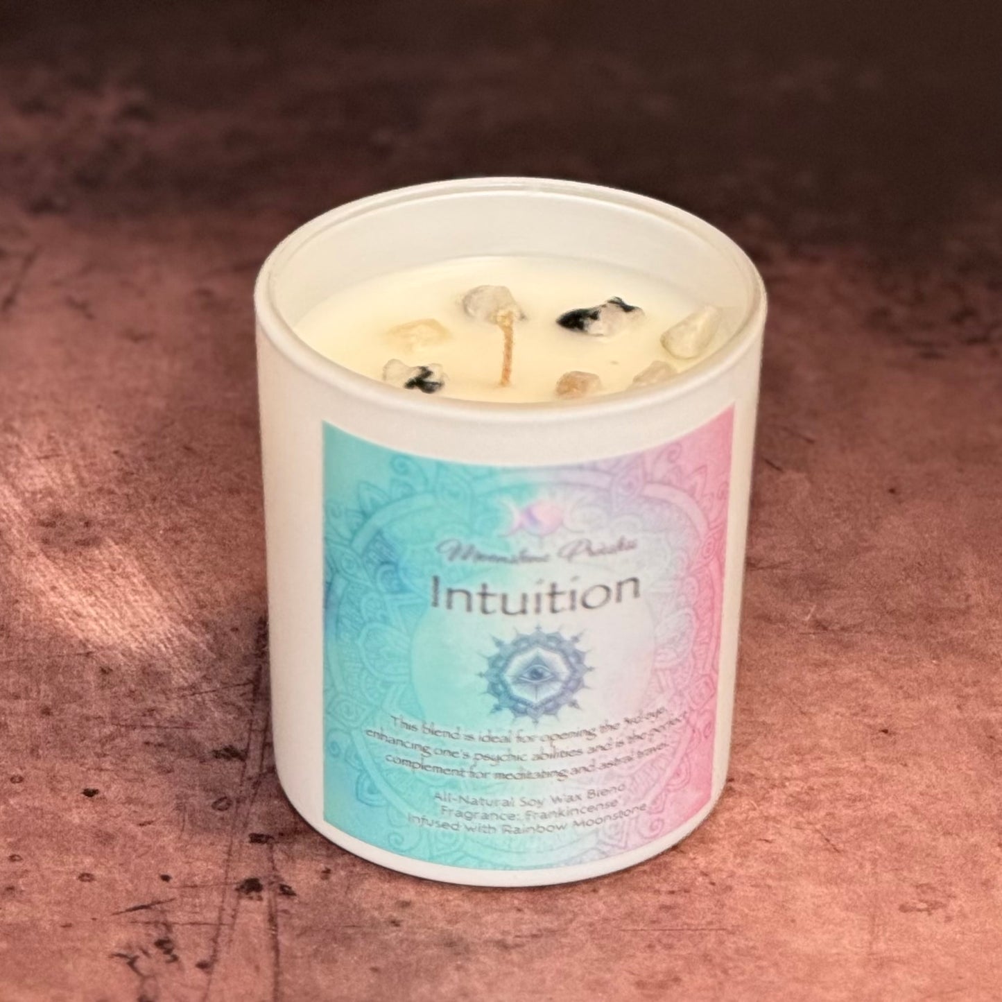 Candle in a white container with 'Intuition' label on a textured brown surface