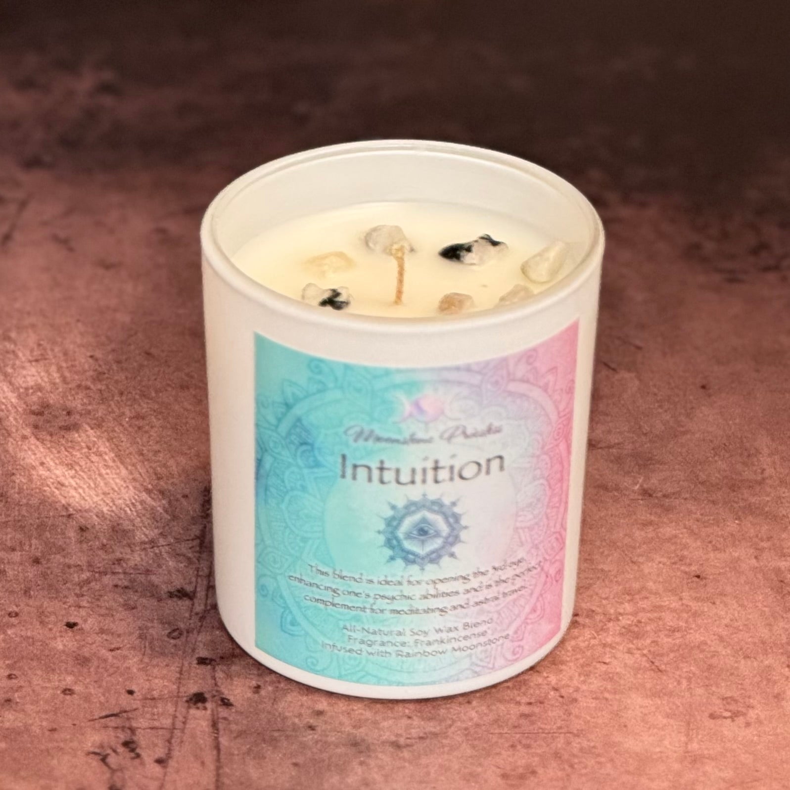 Candle in a white container with 'Intuition' label on a textured brown surface
