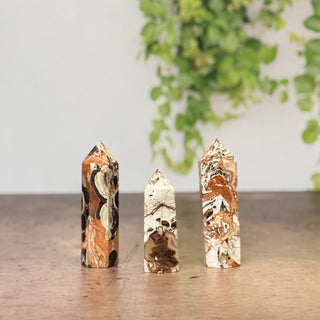 Three marbled stone pillars on a wooden surface with a blurred green plant in the background.