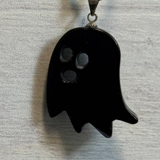 Black ghost-shaped pendant on a gray textured background