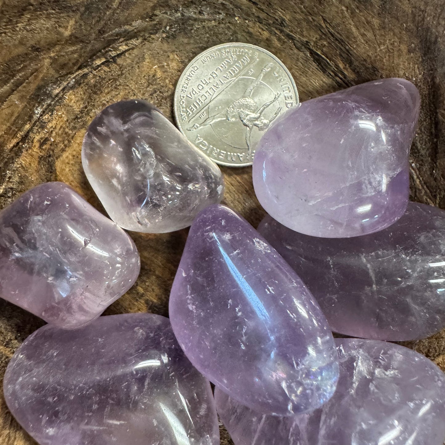 Amethyst crystals with a quarter for scale on a wooden surface