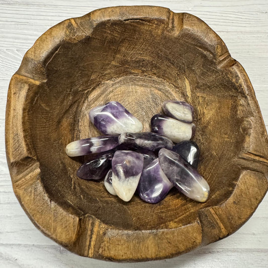 Wooden bowl with amethyst crystals on a light wooden surface