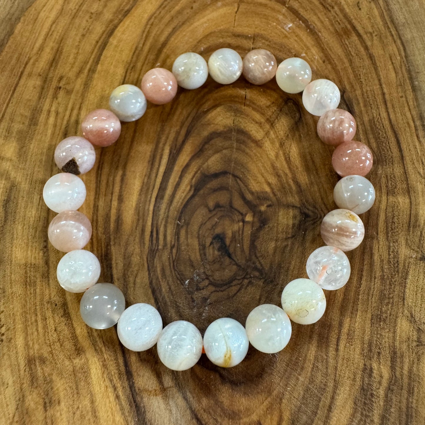 Beaded bracelet with pink and white stones on a wooden surface