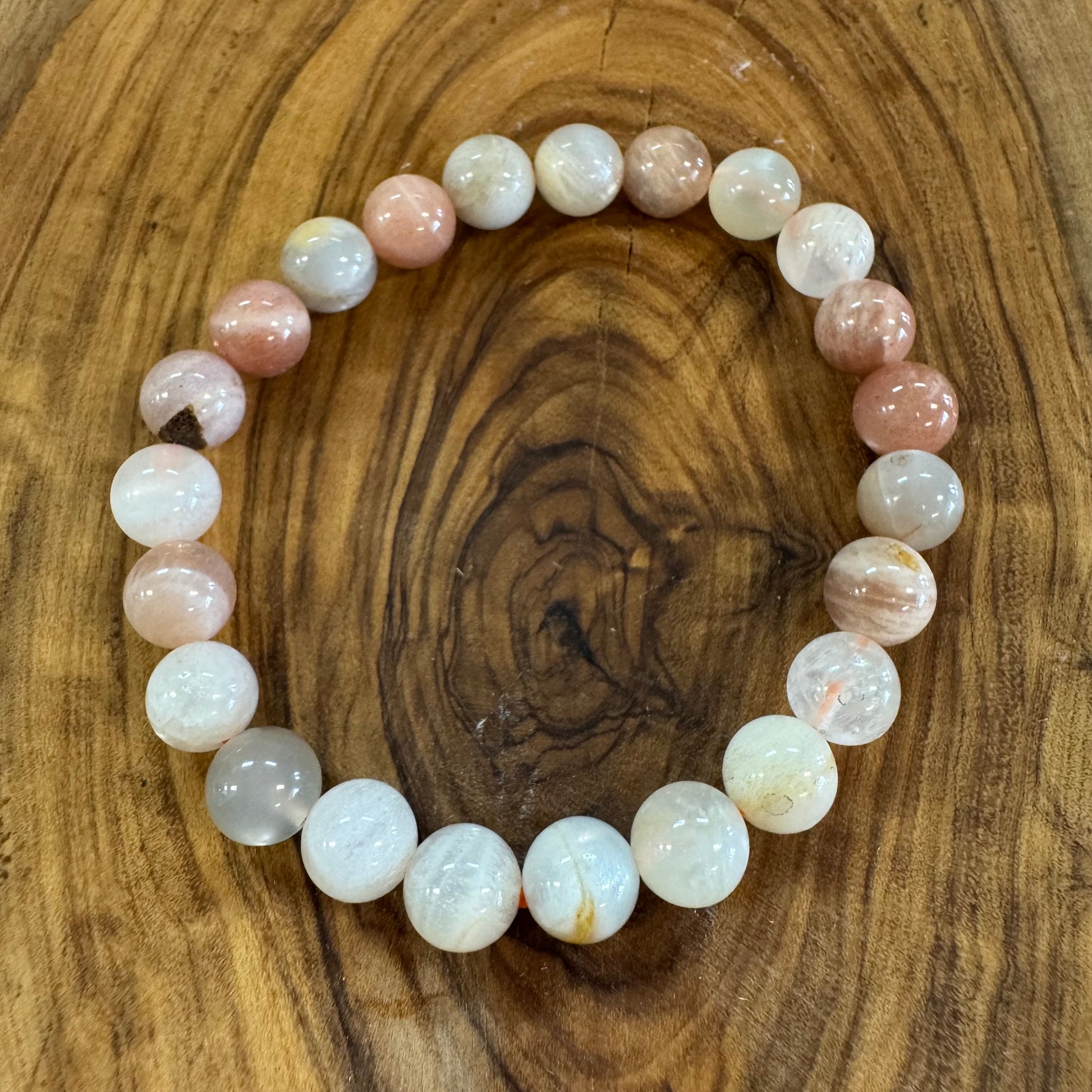 Beaded bracelet with pink and white stones on a wooden surface