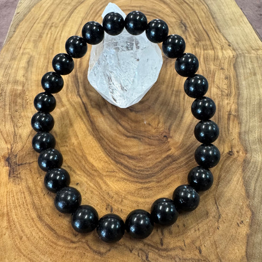 Black beaded bracelet on a wooden surface with a crystal rock