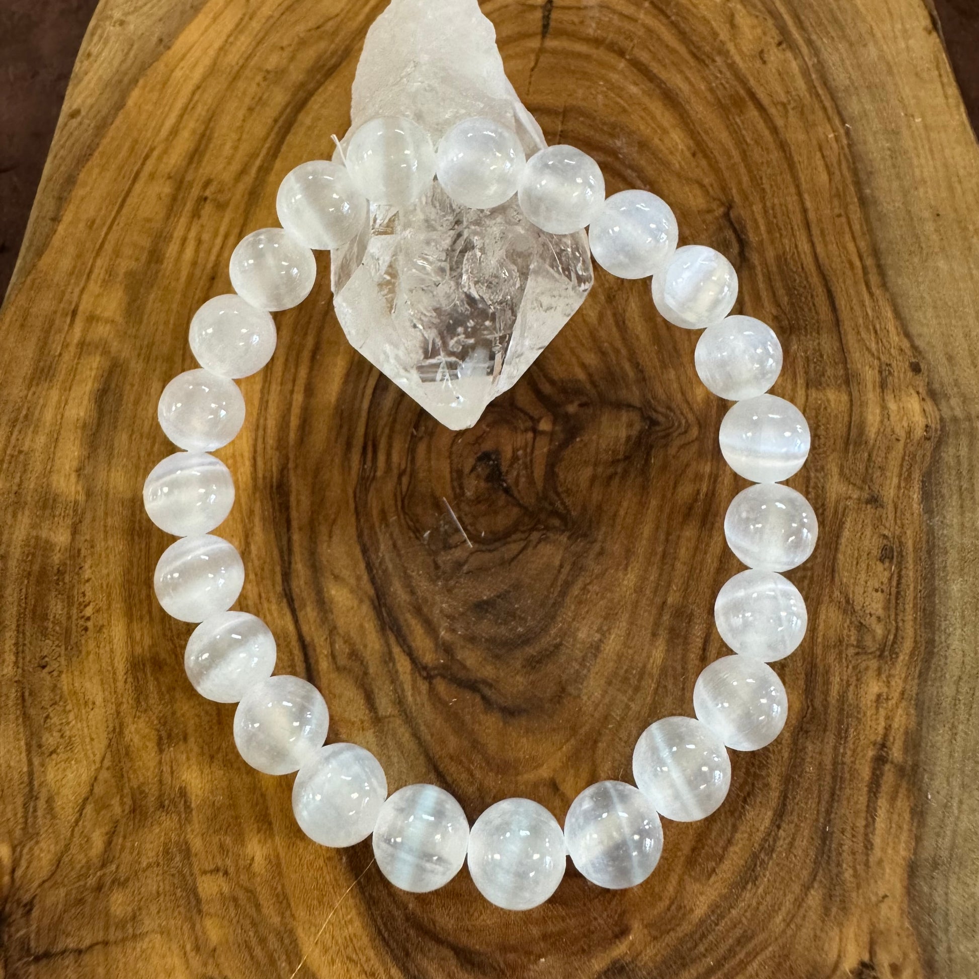 White beaded bracelet on a wooden surface with a crystal
