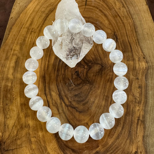 White beaded bracelet on a wooden surface with a crystal