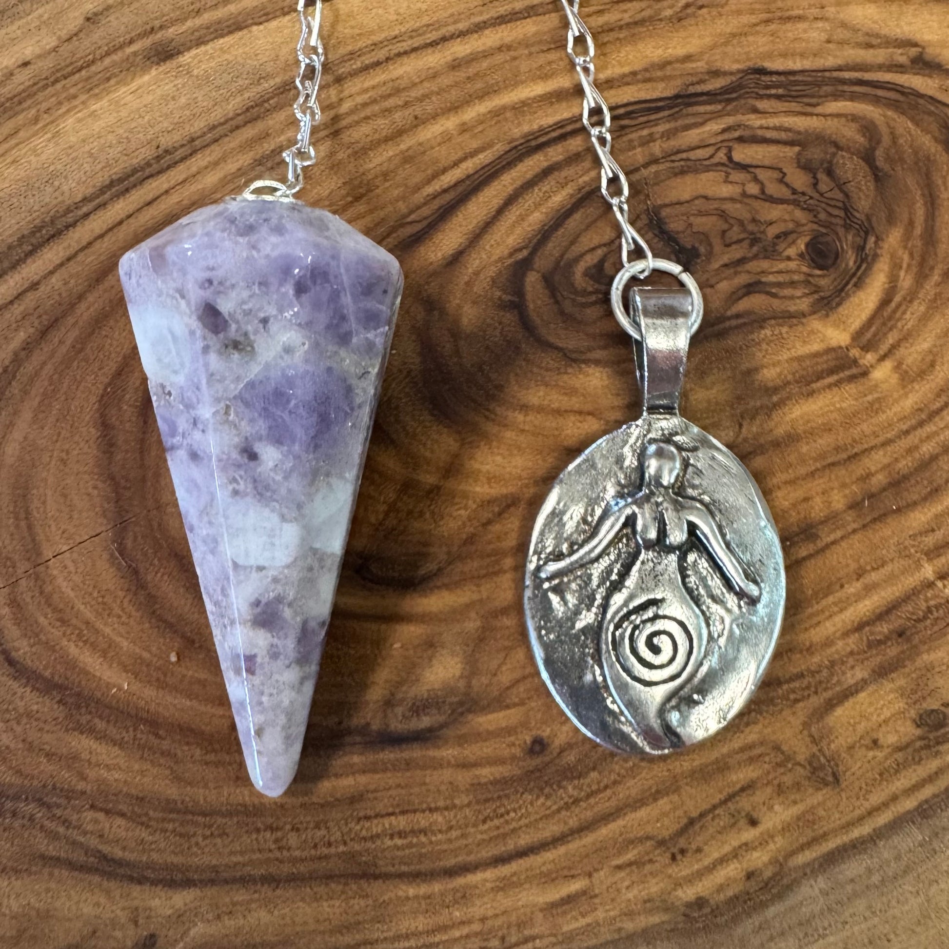 Lepidolite pendulum and silver pendant on a wooden surface