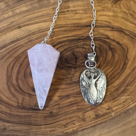 Crystal pendulum and silver pendant on a wooden surface