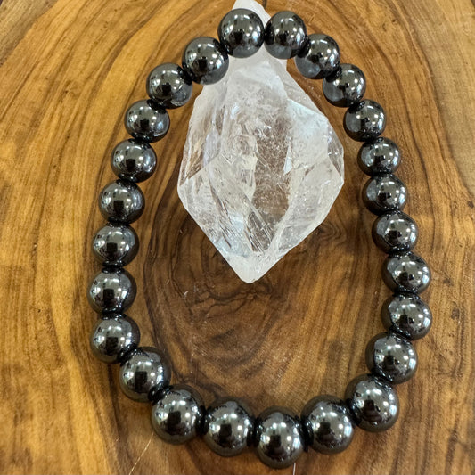 Black beaded bracelet on a wooden surface with a crystal