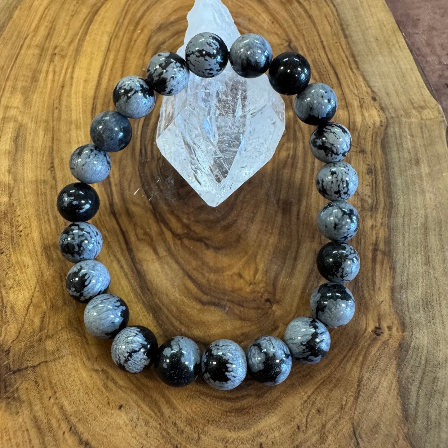 Black and gray beaded bracelet on a wooden surface with a crystal