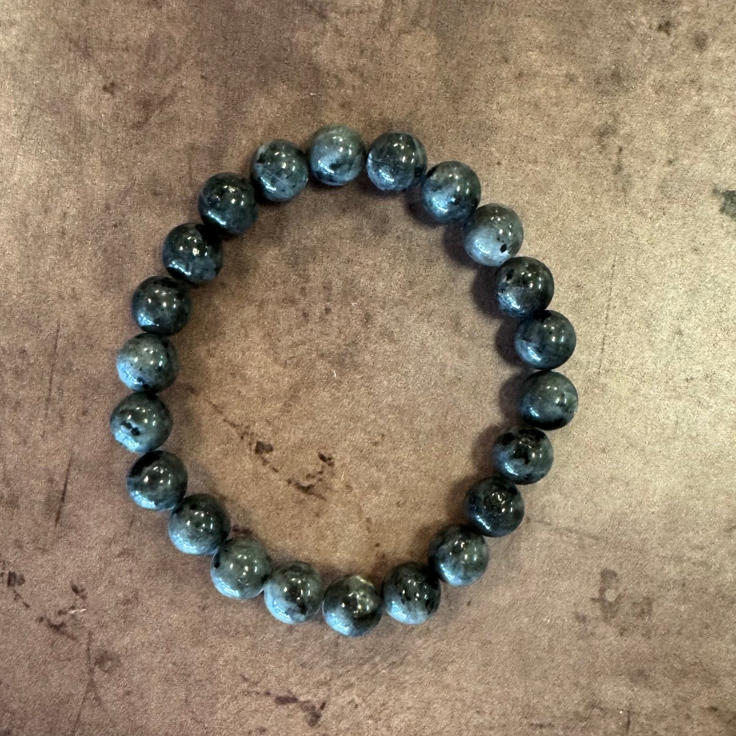 Larvikite beaded bracelet on a textured beige surface