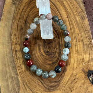 Multicolored beaded bracelet on a wooden surface with a crystal