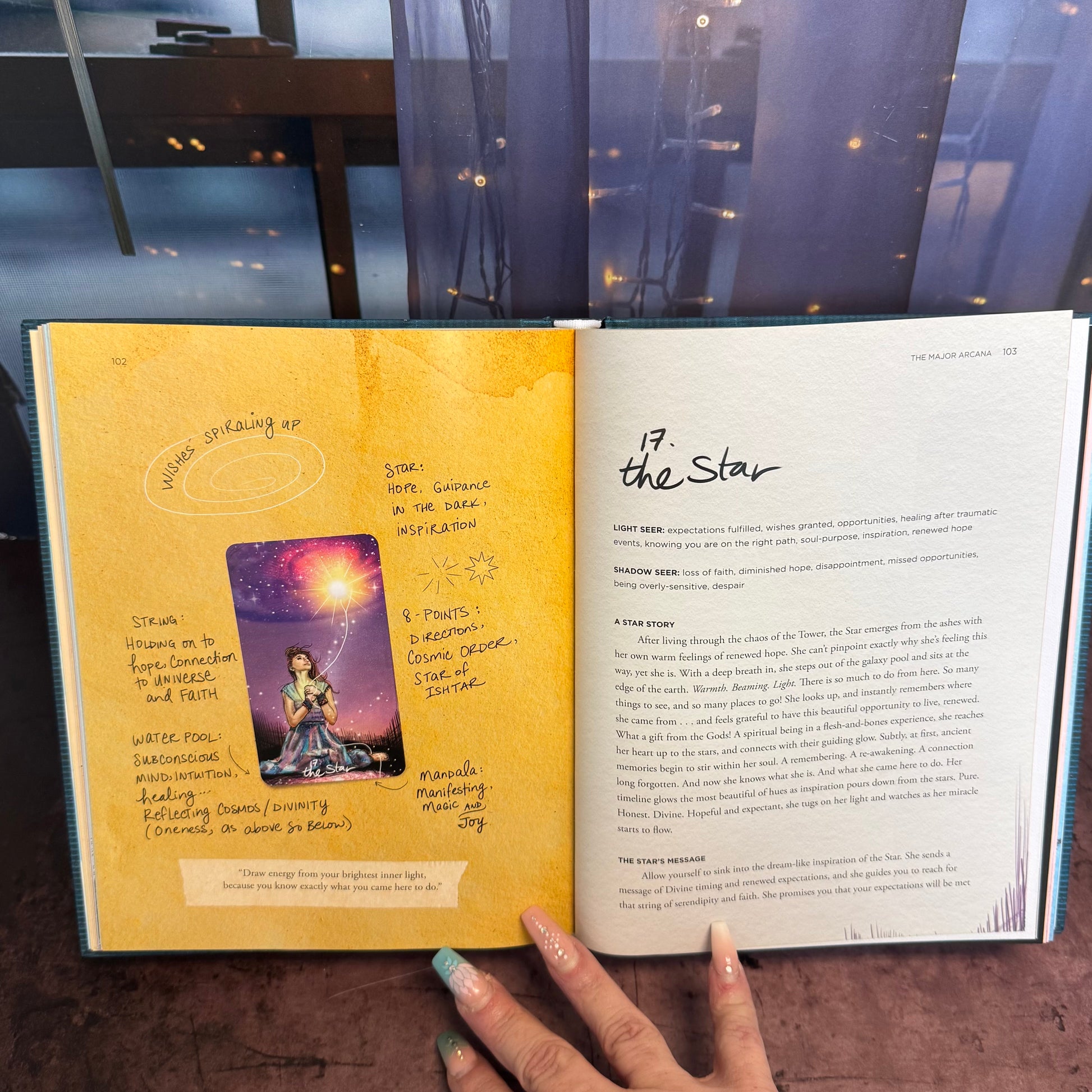 Open book with a yellow page and text, held by a hand on a reflective surface.