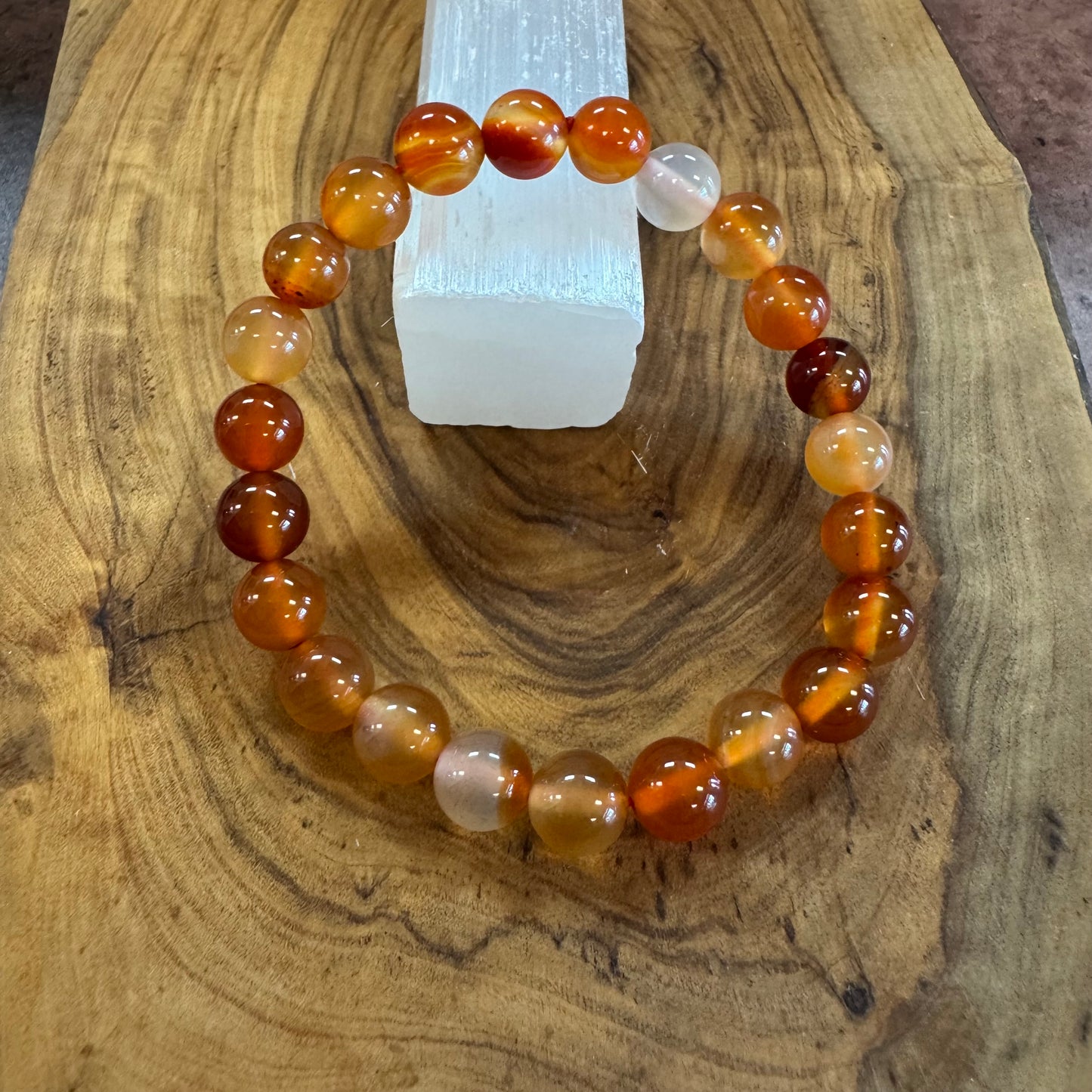 Beaded bracelet with brown, orange, and white beads on a wooden surface