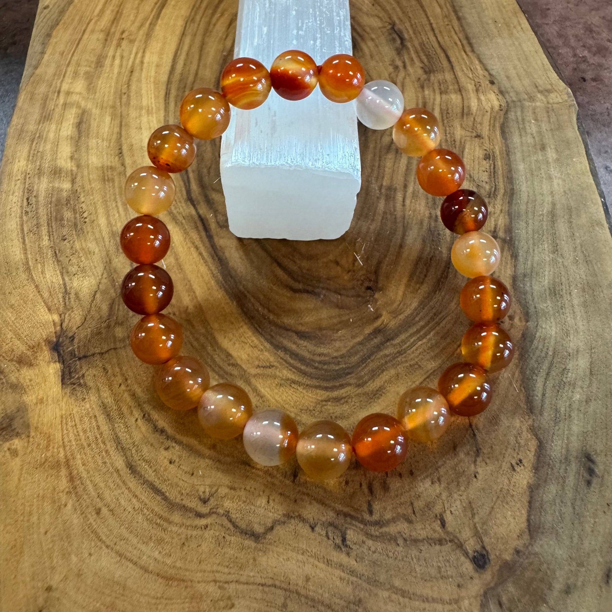Beaded bracelet with brown, orange, and white beads on a wooden surface