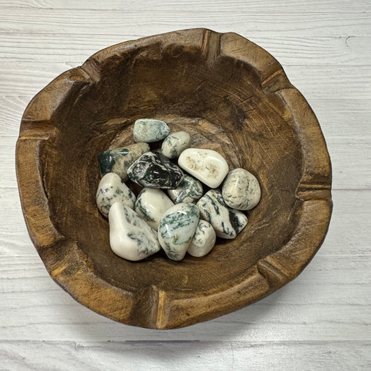 Wooden bowl with pebbles on a light wooden surface