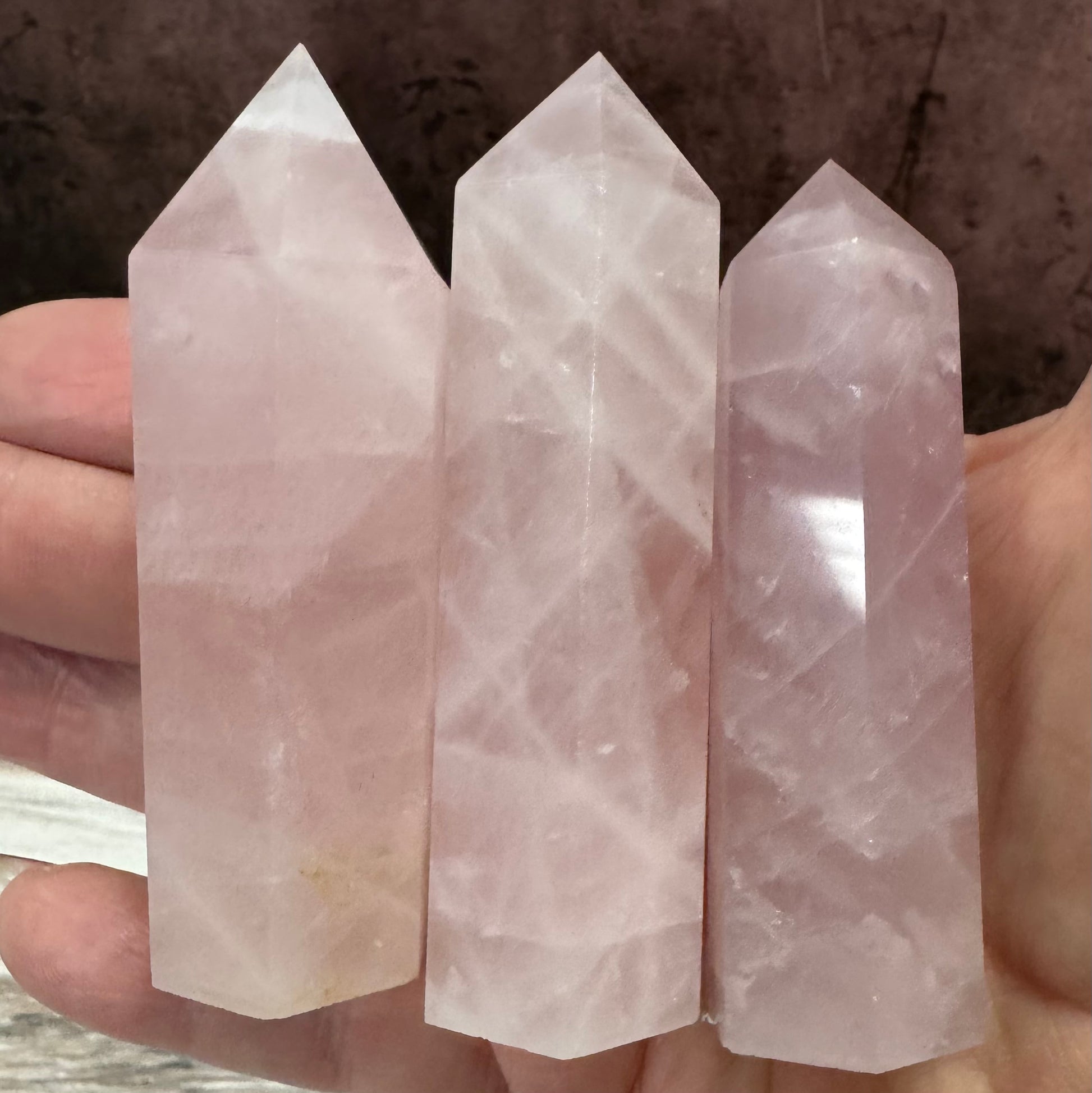 Three crystal points held in a hand against a dark background