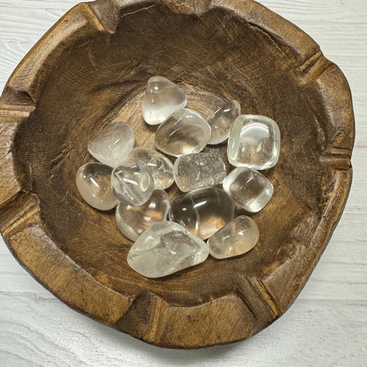 Clear crystals in a wooden bowl on a light wooden surface