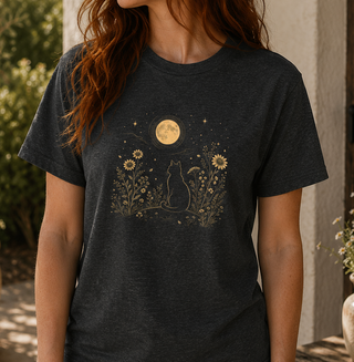 Black Heather Moonlit Cat tee with a gold cat among wildflowers under a full moon, worn outdoors