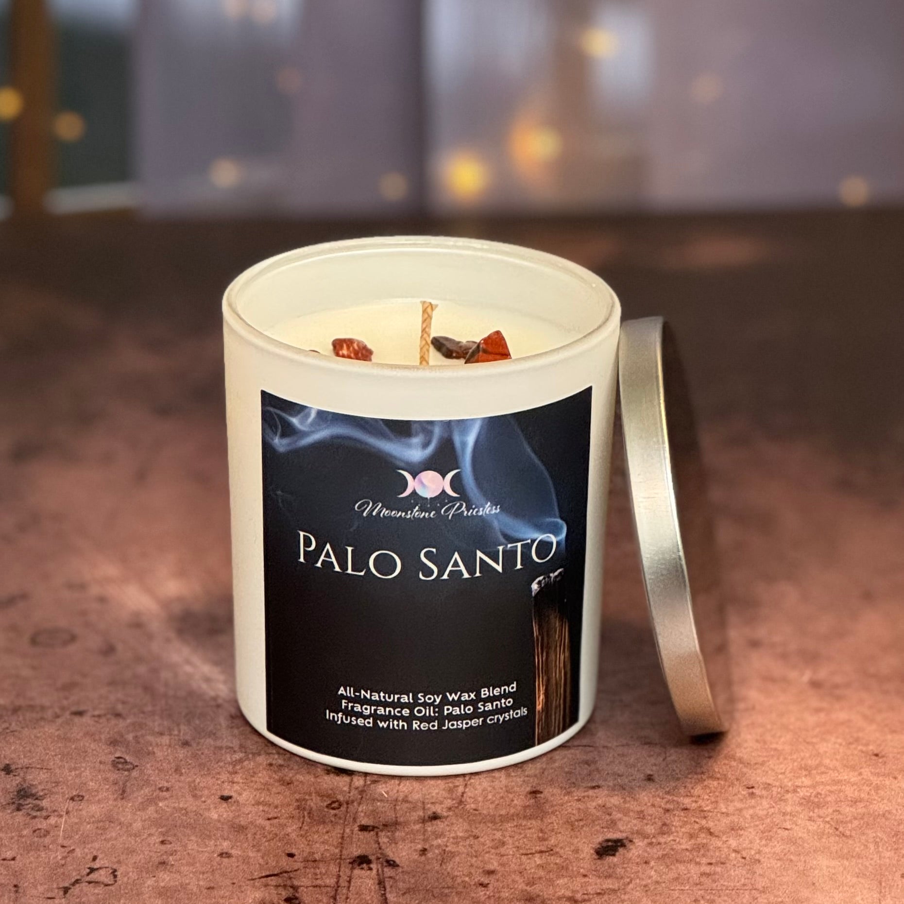 Palo Santo candle in a white container with a black label on a wooden surface.