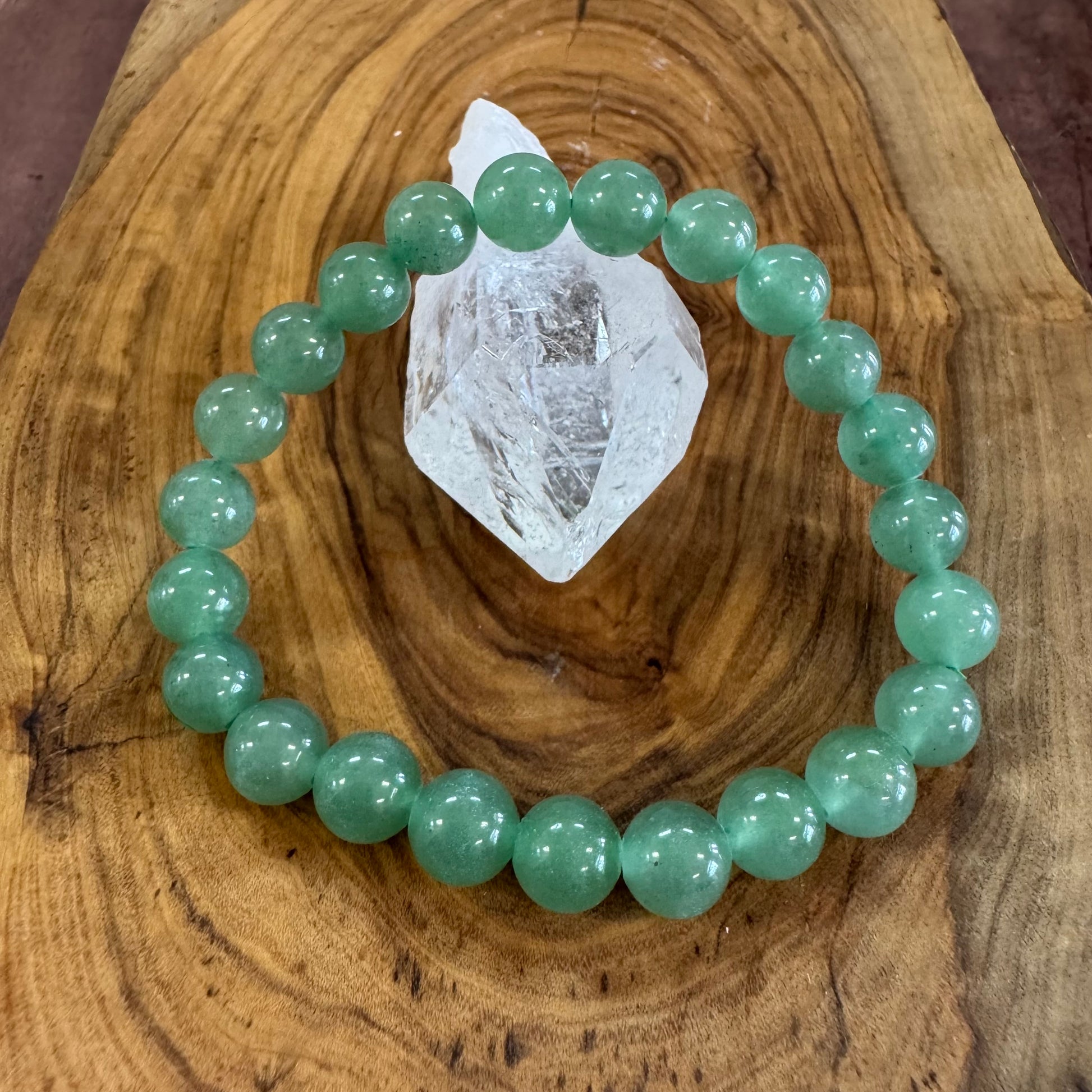 Green beaded bracelet on a wooden surface with a crystal