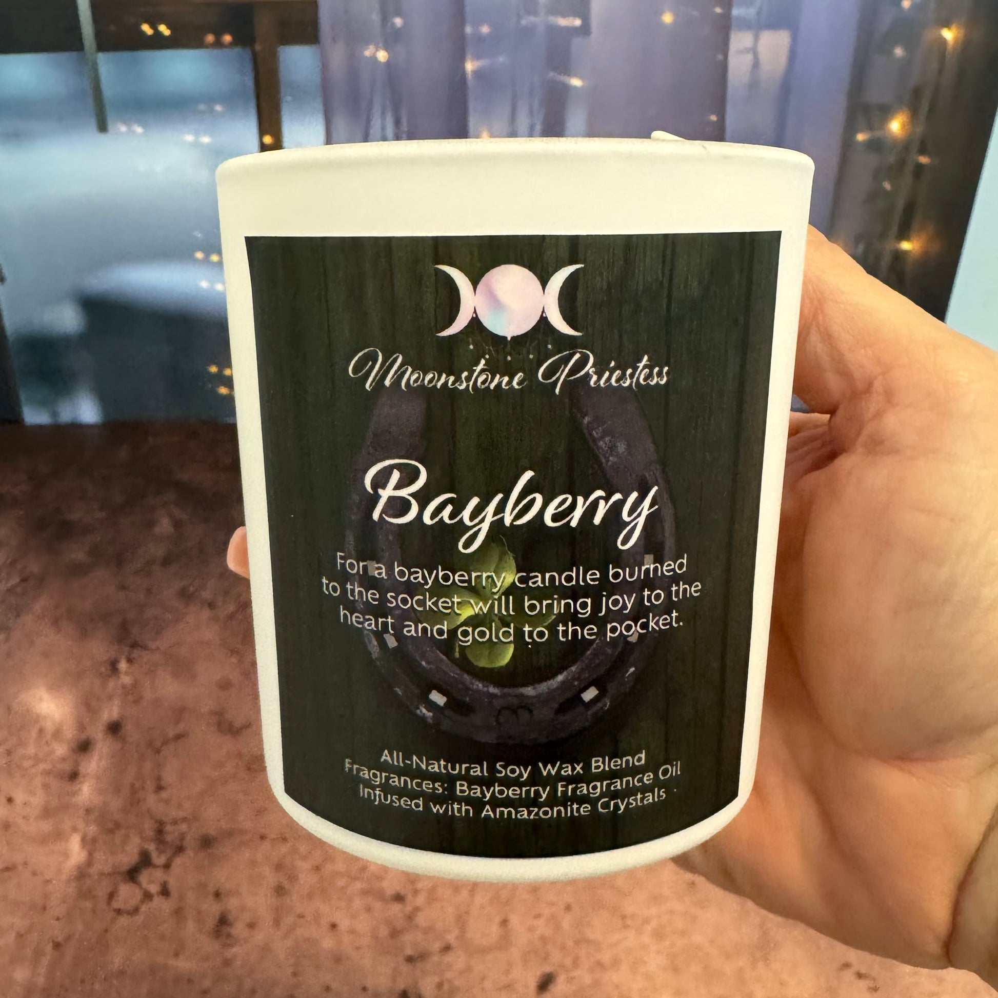 Candle labeled 'Bayberry' held by a hand with a blurred background