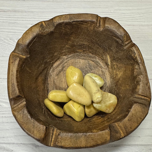 Wooden bowl with stones on a light wooden surface