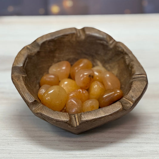 A collection of Golden Azeztulite tumbled stones displayed in a wooden bowl.