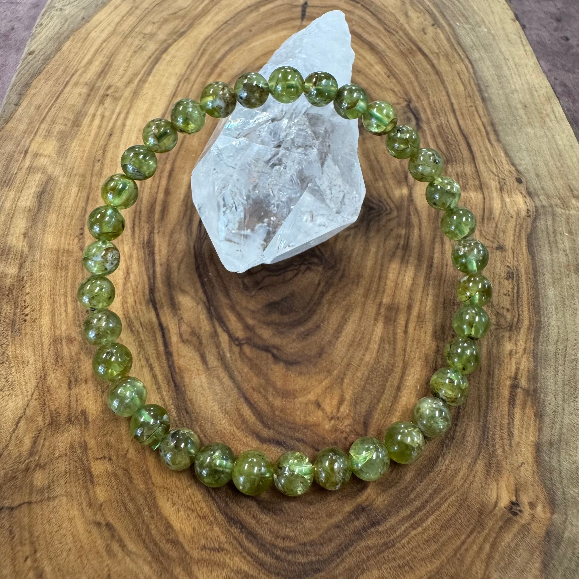 Green beaded bracelet on a wooden surface with a crystal