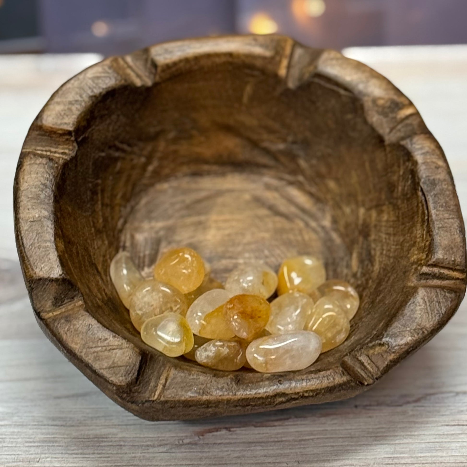 Wooden bowl with yellow stones on a wooden surface