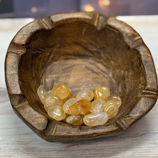 Wooden bowl with yellow stones on a wooden surface