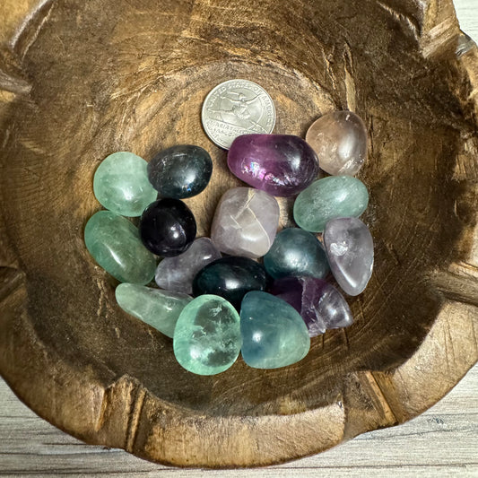 Assorted colorful crystals in a wooden bowl with a coin for scale.