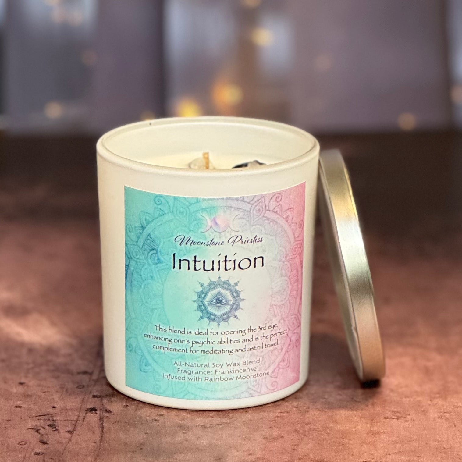 Candle in a decorative container with 'Intuition' label on a wooden surface
