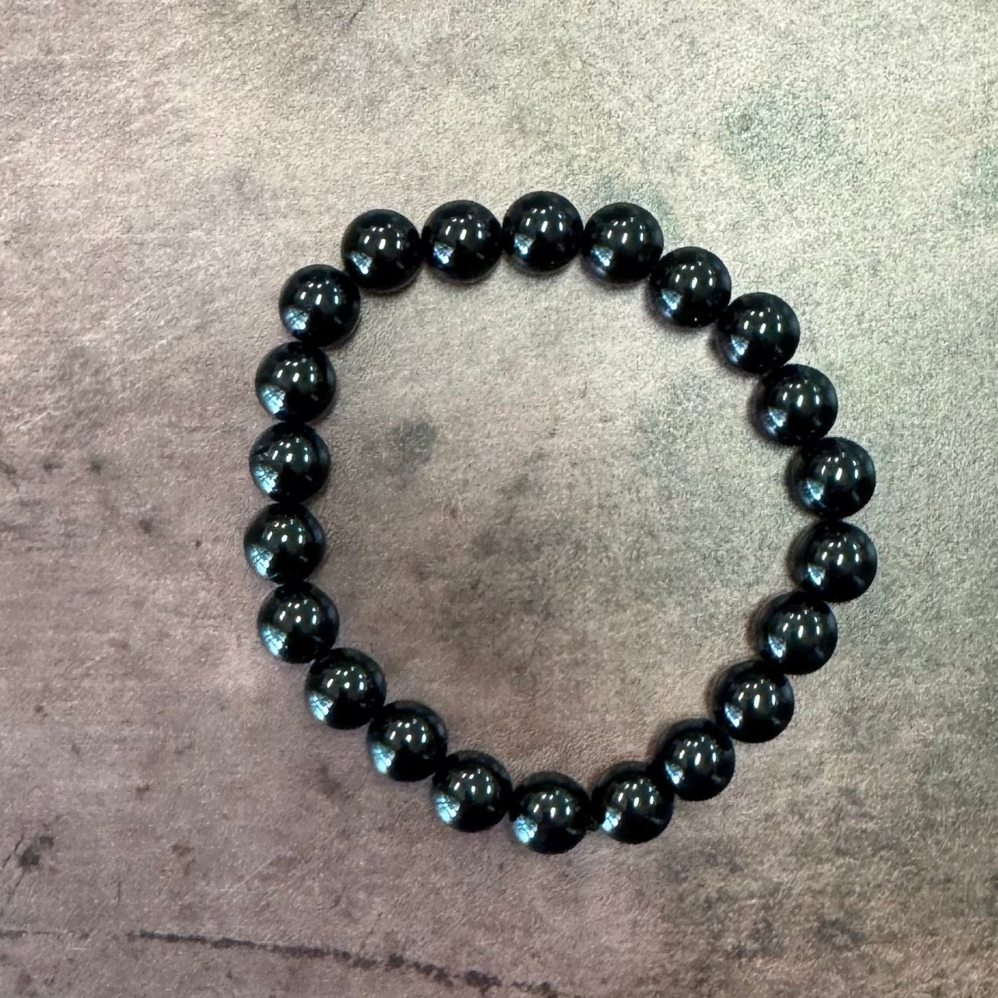 Black beaded bracelet on a textured gray surface